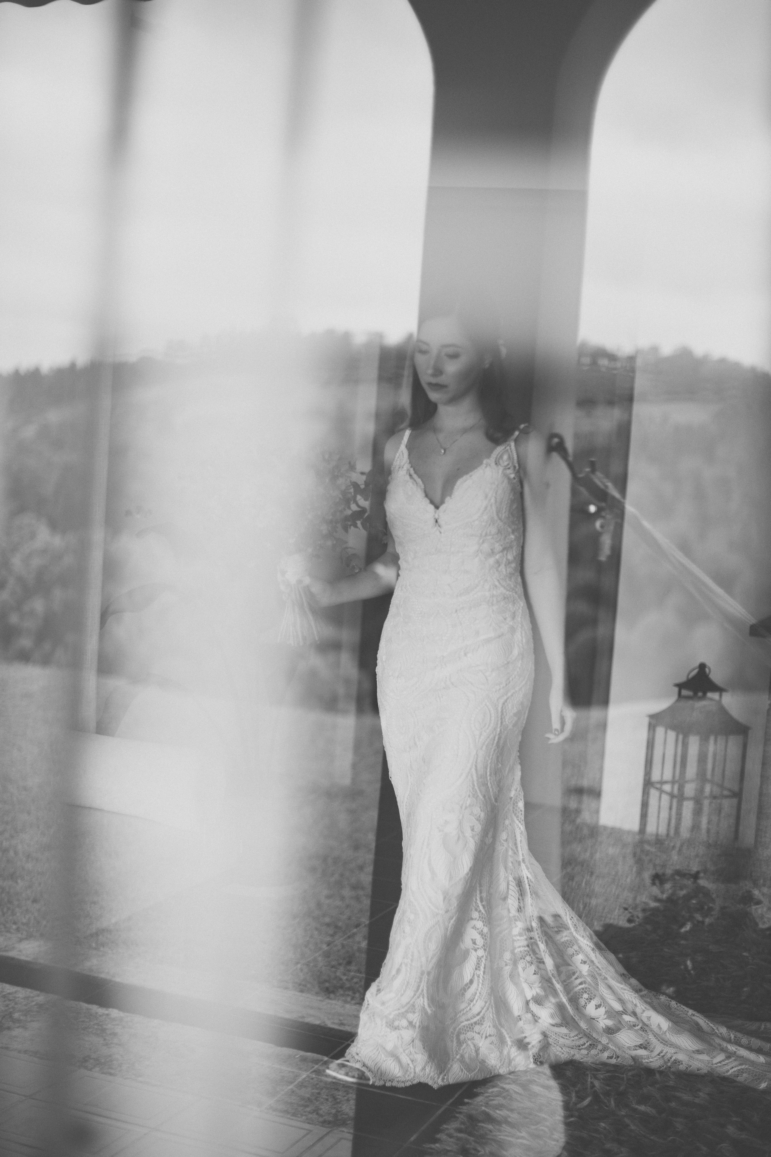 Noiva em preto e branco com vestido de renda posando junto a colunas