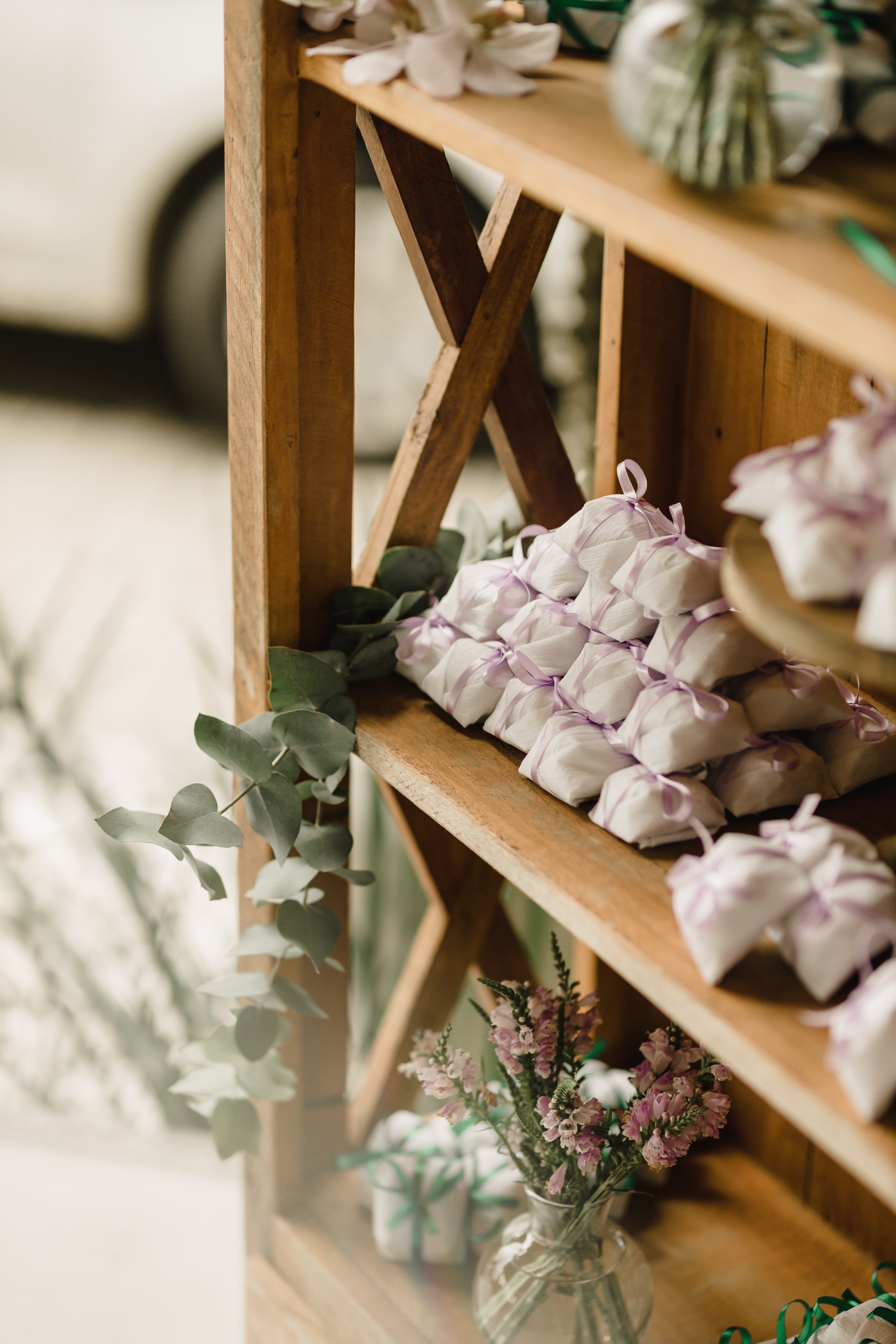 Estante de madeira com lembranças de casamento embrulhadas e flores