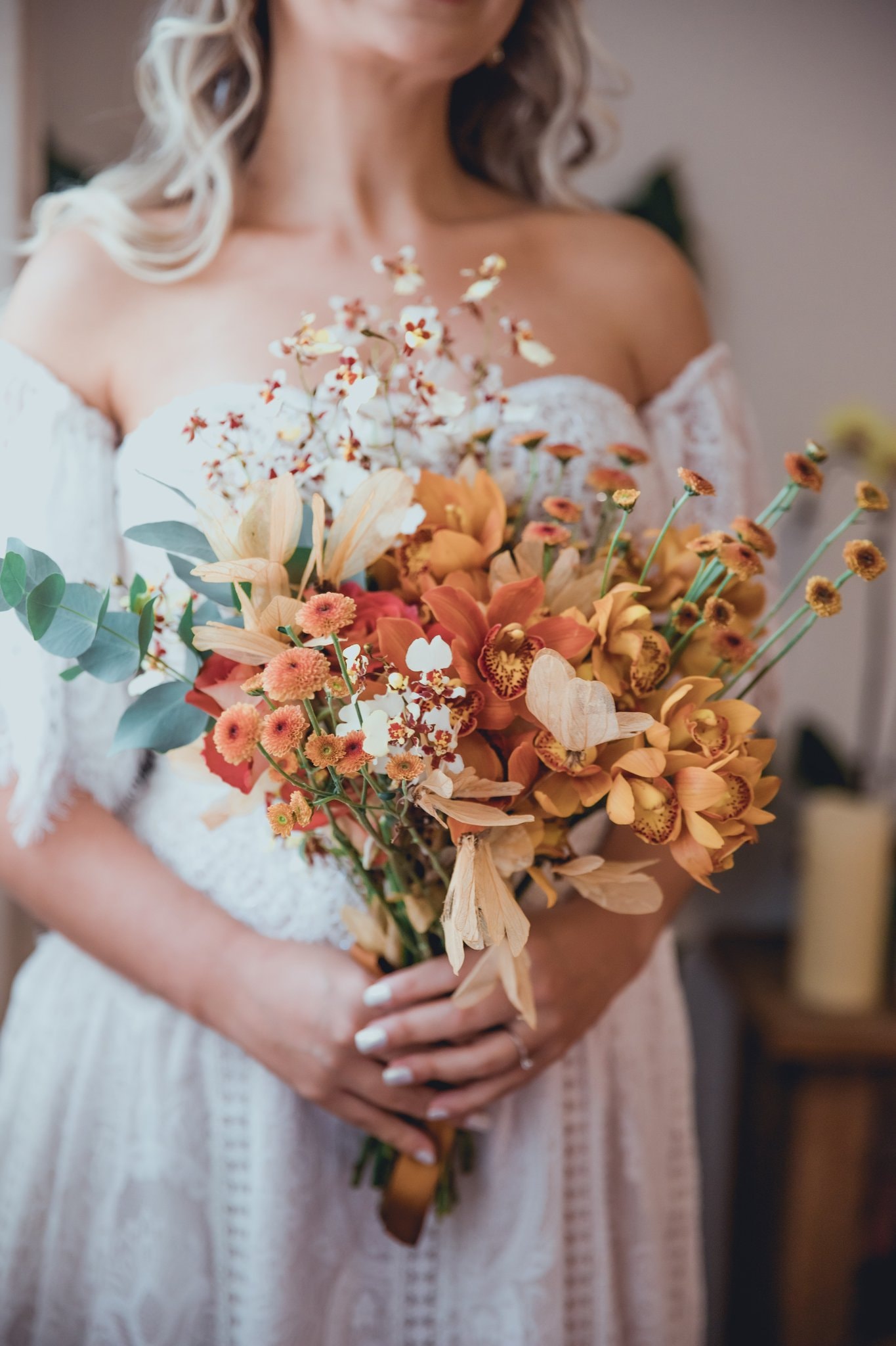Noiva segurando buquê exuberante de orquídeas cymbidium laranja, oncidium e flores silvestres com eucalipto